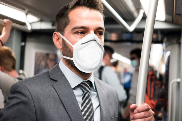 Masked business man riding the subway, coronavirus urban transportation and safety concept - Foto, Imagem