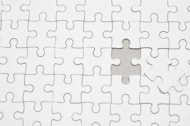 White jigsaw puzzle pattern background. placing last piece of jigsaw puzzle - Φωτογραφία, εικόνα