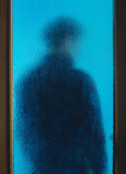 Homme en noir derrière une porte fermée à travers le verre
 - Photo, image