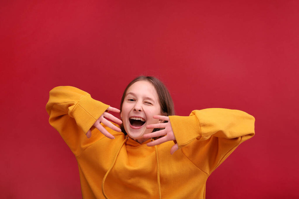 Dancing girl in a sweater on a red background. - Φωτογραφία, εικόνα