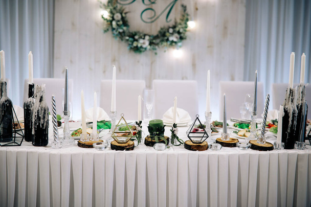 Κίεβο / Ουκρανία - 06 / 22 / 2018 - Γαμήλια διακόσμηση. Ρουστίκ γκρι διακόσμηση γαμήλιας αίθουσας με φρέσκα λουλούδια. Τραπέζι με πολλά κεριά και vintage κηροπήγια - Φωτογραφία, εικόνα