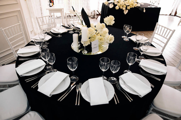 Kiev / Ukraine - 08/08/2019 - Wedding decor. The process of decorating a classic-style wedding hall in black and white with fresh flowers in the middle of the table - Photo, Image