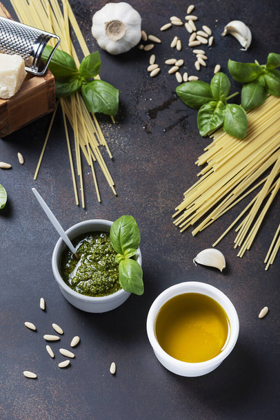 Condiments for cooking italian pasta: spaghatti, basil, olive oil, garlic and pine nuts on the black table. Top view image with a copy sppace - Valokuva, kuva