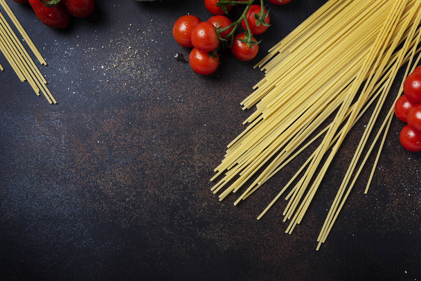 Ingredients for cooking italian pasta: spaghetti, tomato and garlic on the black table. Top view image with a copy space - Foto, imagen