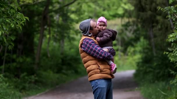 Papa met een dochter in haar armen in het park spelen. - Video