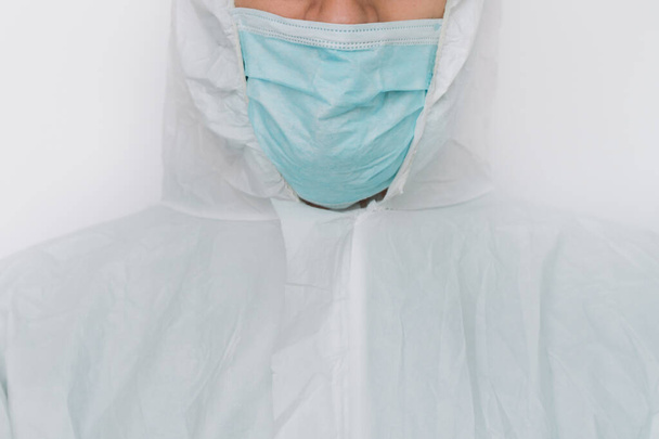 Virologist is weaing in protective clothe during coronavirus pandemic, portrait. Suit, mask, gloves and glasses on white background in clinic or hospital - Photo, image