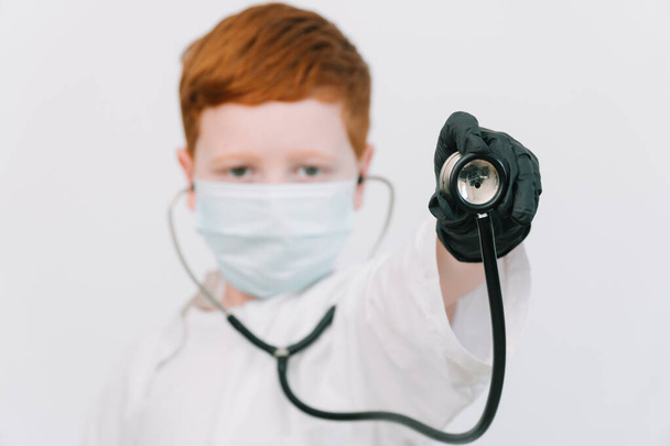 Close up of caucasian littile doctor with a stethoscope in protective mask. Reception of a patient with pneumonia - Фото, зображення
