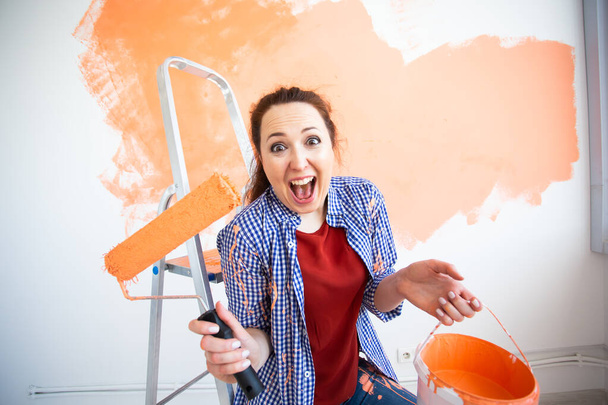 Αστεία νεαρή γυναίκα με ρολό ζωγραφικής σε εσωτερικούς χώρους. Ανακαίνιση, ανακαίνιση, επισκευή διαμερισμάτων και αναψυκτικό. - Φωτογραφία, εικόνα