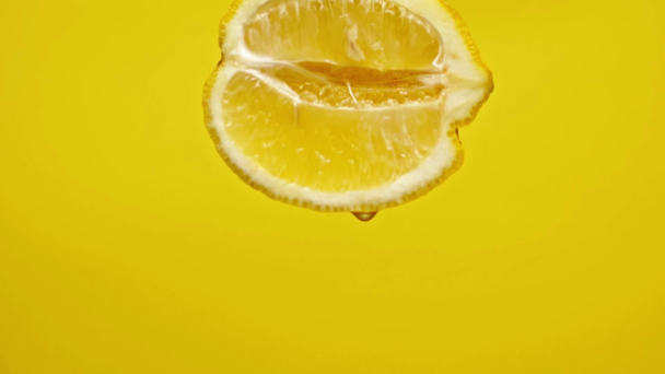 gotas jugosas goteando de limón medio aislado en amarillo, cámara lenta
 - Imágenes, Vídeo