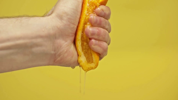 mano masculina apretando naranja aislado en amarillo, cámara lenta
 - Metraje, vídeo