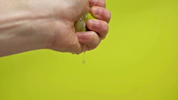 male hand squeezing lime juice isolated on green, slow motion - Footage, Video