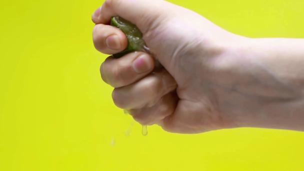 male hand squeezing lime juice isolated on green, slow motion - Footage, Video