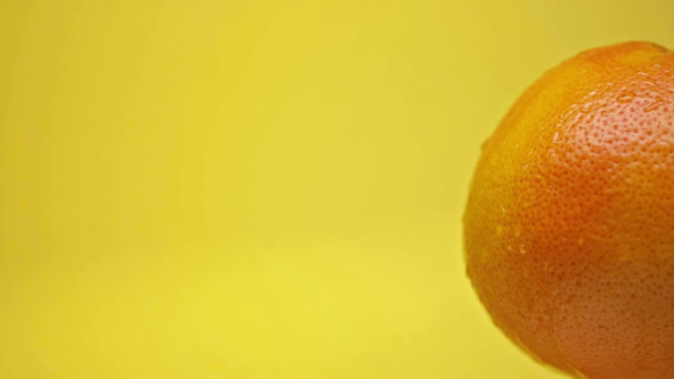 krople spadające na całą dojrzałą pomarańczę wyizolowane na żółto - Materiał filmowy, wideo