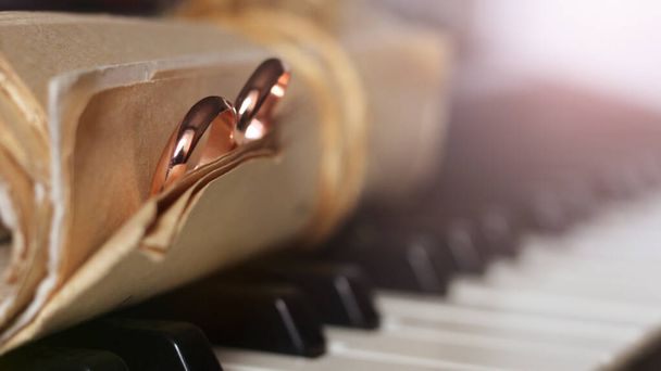 İki altın alyans ve eski müzik notaları, piyano tuşları - Fotoğraf, Görsel