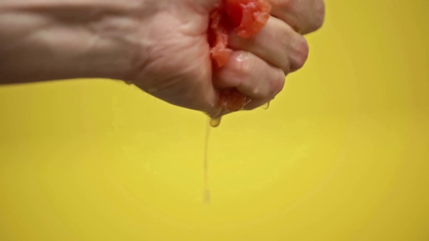 male hand squeezing grapefruit isolated on yellow, slow motion - Footage, Video