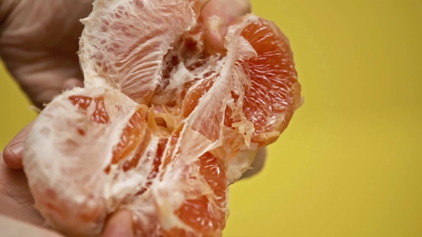 abgeschnittene Ansicht eines Mannes, der saftige Grapefruit isoliert auf gelbem Papier in Zeitlupe hält - Filmmaterial, Video