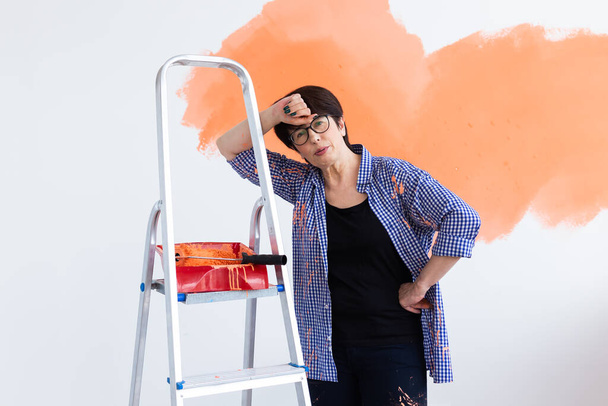 Femme d'âge moyen peignant les murs d'une nouvelle maison. Concept de rénovation, réparation et redécoration. - Photo, image