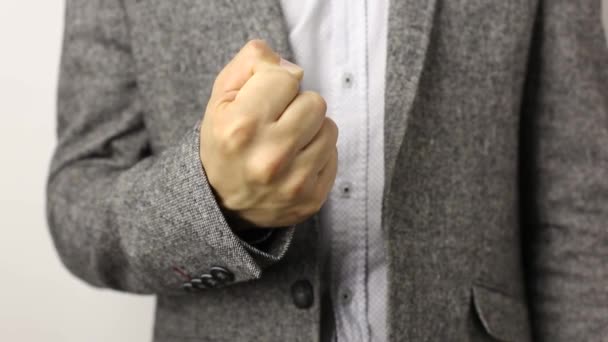 Hombre sólido con chaqueta gris sobre fondo blanco levantando el puño. gesto de amenaza, concepto de agresión, advertencia, castigo
 - Imágenes, Vídeo