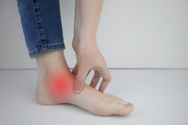 Woman suffering from heel pain. Inflammation or sprain of the tendon in the foot, heel spur, bursitis. The concept of diseases and pains in the leg - Photo, Image