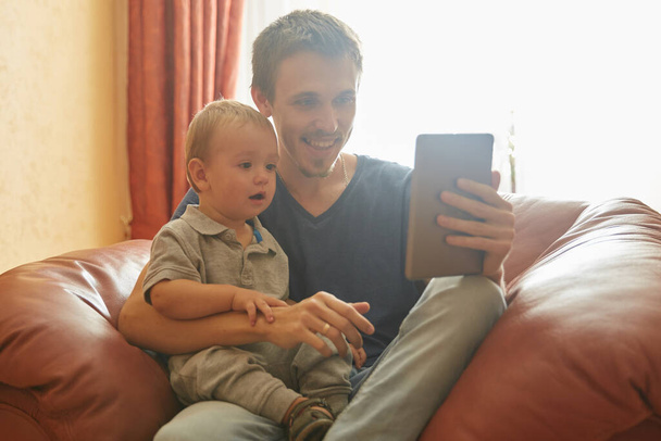 Ευτυχισμένος πατέρας του μωρού γιος βλέποντας βίντεο στο τηλέφωνο - Φωτογραφία, εικόνα