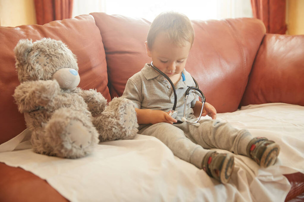 Chłopiec dziecko bawiące się stetoskopem siedzieć na fotelu - Zdjęcie, obraz
