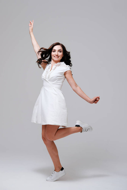 young woman in white dress and sneakers jumping - Foto, Bild