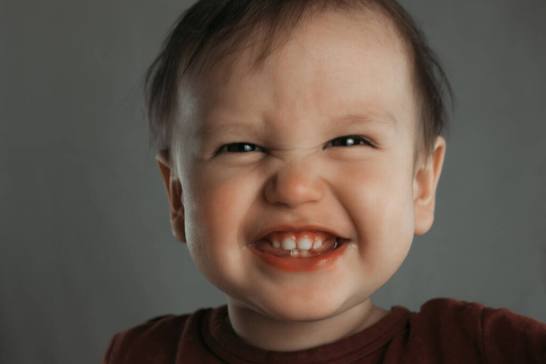 Retrato de um menino rindo bonito em um fundo cinza
 - Foto, Imagem
