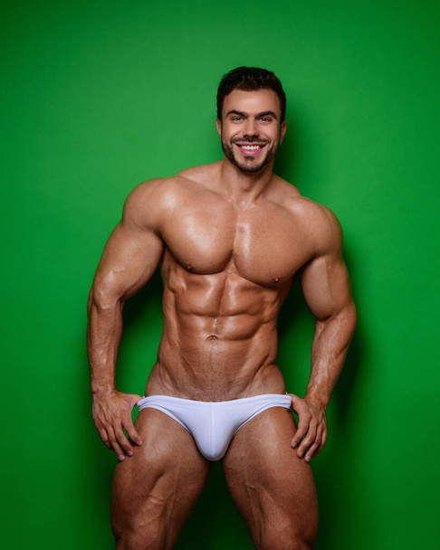 Sorridente modello maschile in costume da bagno bianco su sfondo verde
 - Foto, immagini