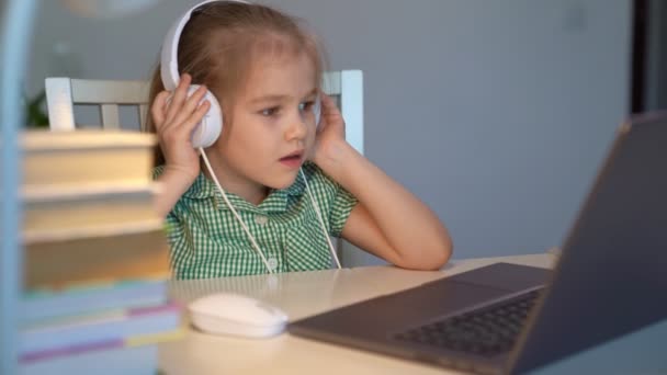 kid girl in headphones listens to music or lesson, distance online learning home - Video, Çekim