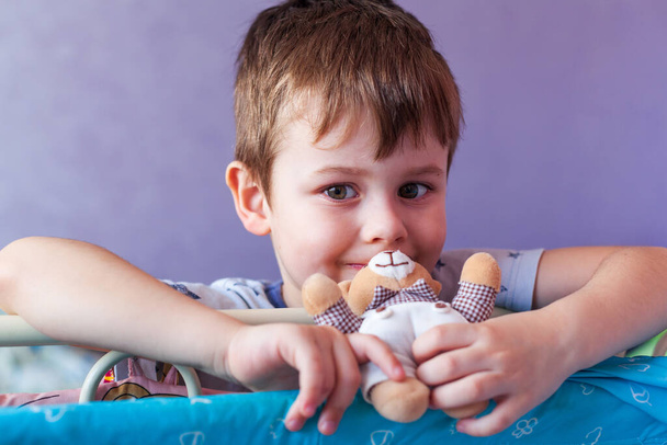 Child Holding little Teddy Bear toy. Little cute boy holding a soft toy at front of face looking at camer - Foto, Imagen