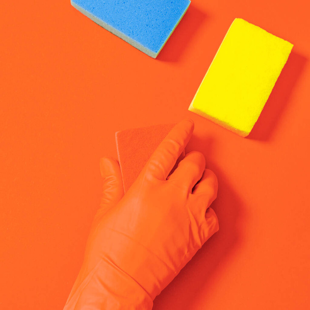 Cleaning concept. Hand in glove with washcloth wipes colored surface on which lie multi-colored washcloths - Photo, Image