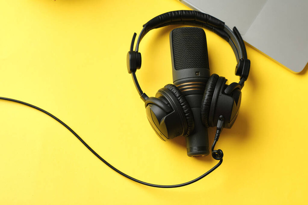 Flat lay composition with Microphone for podcasts  and black studio headphones on yellow background, learning online education concept - 写真・画像