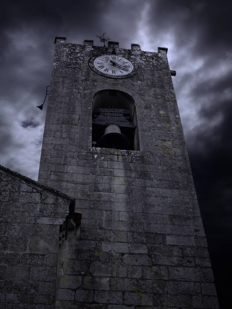 Oude granieten klokkentoren van de moederkerk. Middeleeuwse stad Ponte de Lima, Noord-Portugal, op een bewolkte nacht. - Foto, afbeelding