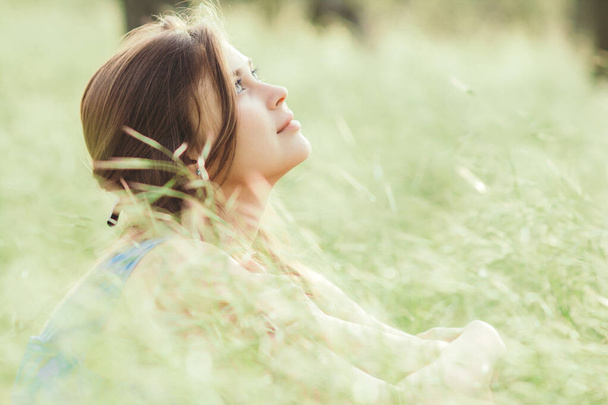 beautiful romantic girl sitting on field of spikelets and enjoying nature, young elegant woman walking - Foto, Bild