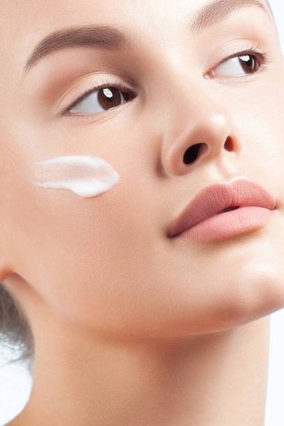 Young beautiful woman applies cream on clean perfect skin.  Beauty portrait close-up - Fotografie, Obrázek
