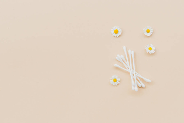 Cotton swabs and fresh chamomile on a beige background. Flat lay, top view, copy space. - Photo, Image