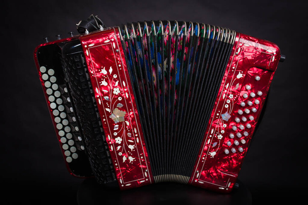 Russian folk instruments.Red bayan on a black background.Russian accordion  - Photo, Image