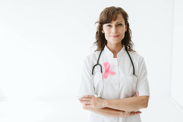 Young doctor wearing pink ribbon on a white uniform - Fotó, kép