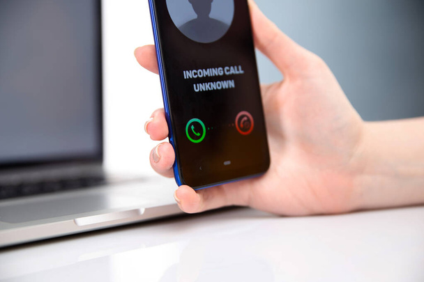 Frau hält Telefon mit eingehendem unbekannten Anruf isoliert. - Foto, Bild