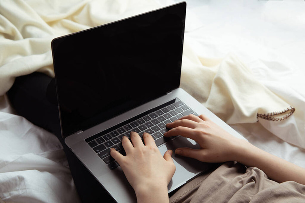 Работа на дому концепции. Женщина печатает на компьютере в кровати
. - Фото, изображение