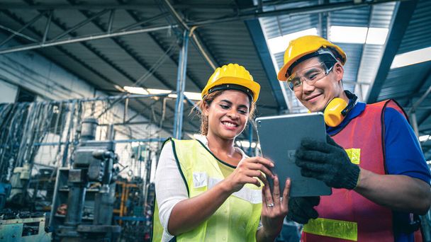 Dois trabalhadores industriais multiétnicos olhando para tablet no armazém
. - Foto, Imagem