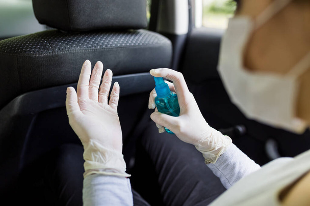 Młoda kobieta stosująca dezynfektor ręczny we wnętrzu samochodu, koncepcja ochrony covid-19. - Zdjęcie, obraz