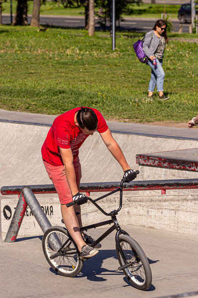 26.05.2018, Moscow, Russia. A teenager boy in a red t-shirt does tricks on a special bike at a skatepark. Active lifestyle of modern russian children. - Zdjęcie, obraz