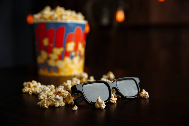 Popcorn egy színes tál és 3D-s szemüveg fa háttér. Támogatási koncepció. - Fotó, kép