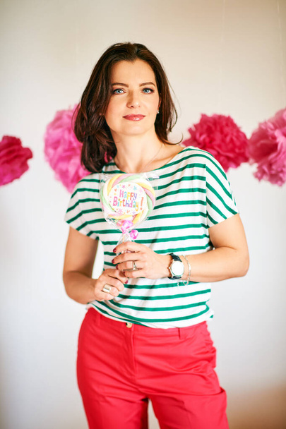 Beautiful cheerful woman holding candy with sign Happy Birthday, party concept - Zdjęcie, obraz