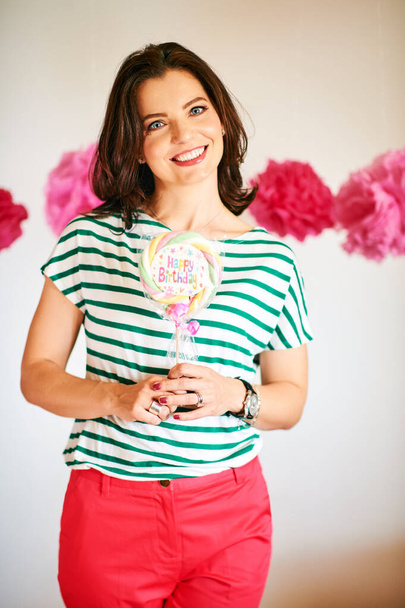 Beautiful cheerful woman holding candy with sign Happy Birthday, party concept - Fotó, kép