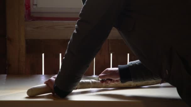 Primo piano processo di uomo facendo bastone di legno all'interno durante la quarantena. Bastone di legno intaglio sul tavolo con coltello - Filmati, video