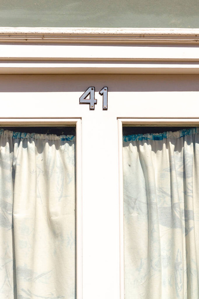 Σπίτι νούμερο 41 σε μια λευκή ξύλινη μπροστινή πόρτα με παράθυρα και κουρτίνες στο Λονδίνο - Φωτογραφία, εικόνα