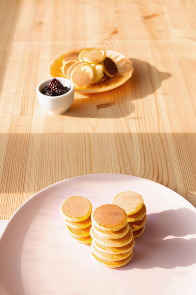 Stacks trendy tiny pancakes on pink plate. - Zdjęcie, obraz
