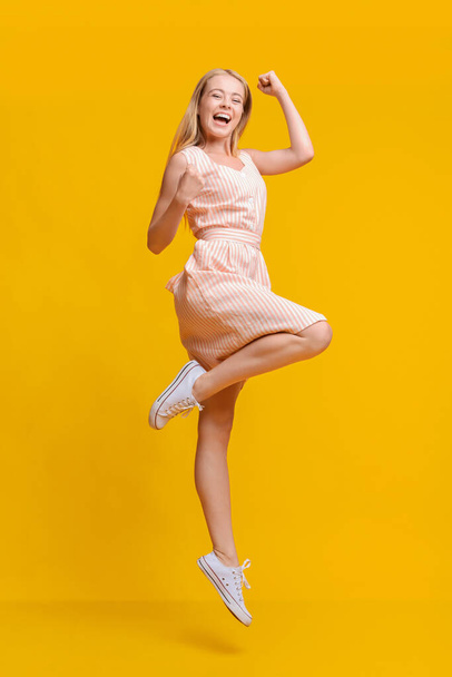 Overjoyed young woman jumping in air, celebrating success with raised fists - Foto, afbeelding